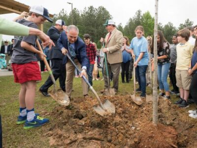 Pruitt plants tree with schoolkids